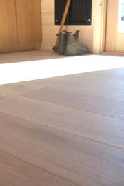 Sun shining on white oak flooring by Stuga with Blundstone boots in the background