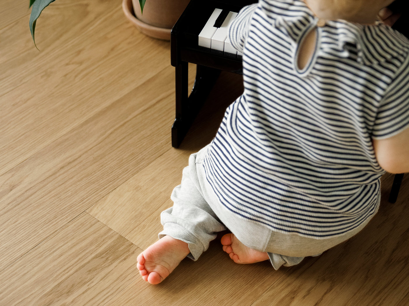 Baby on waterproof hardwood flooring in a striped shirt