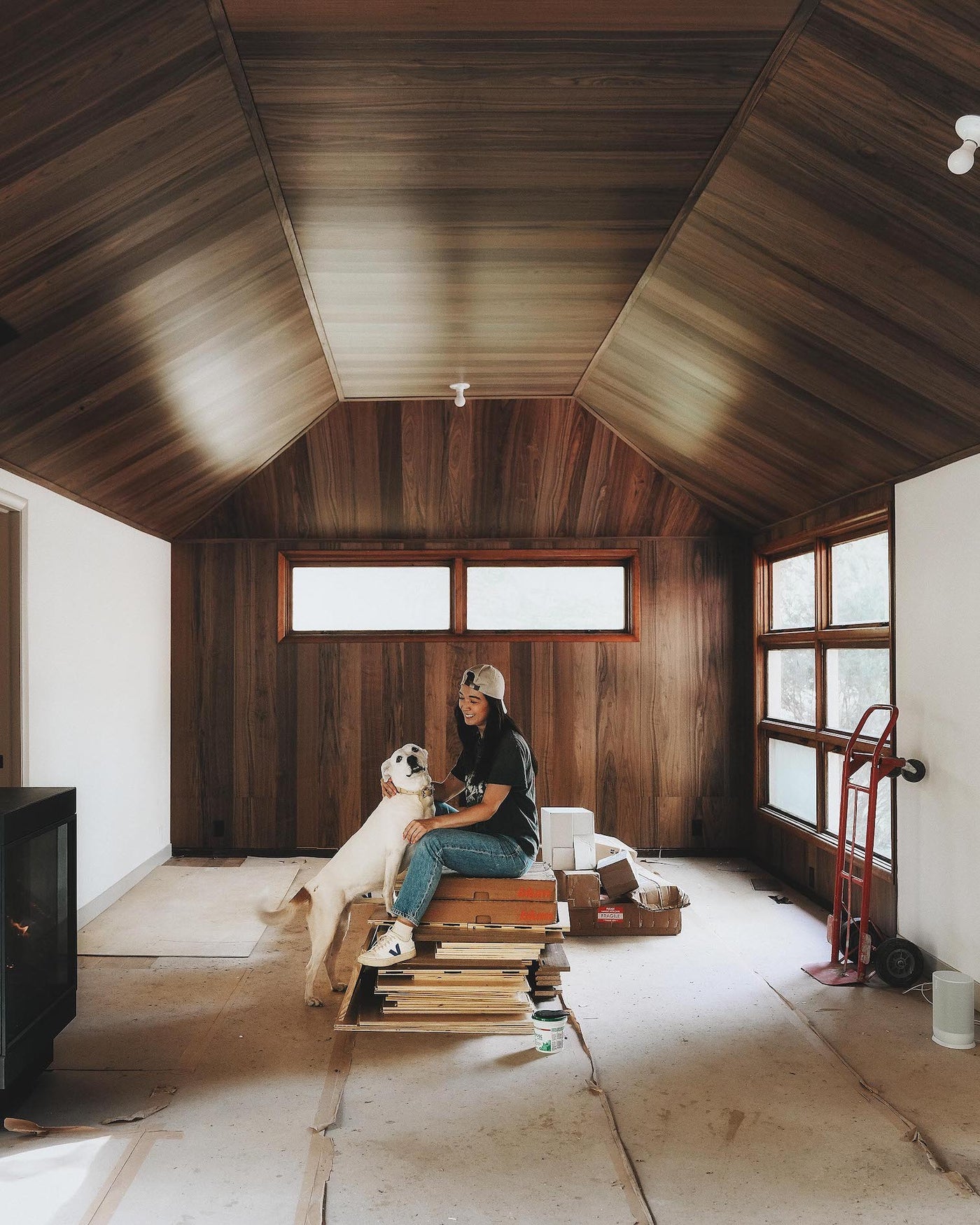 Woman and dog in unfinished living room with walnut feature wall and walnut flooring on ceiling