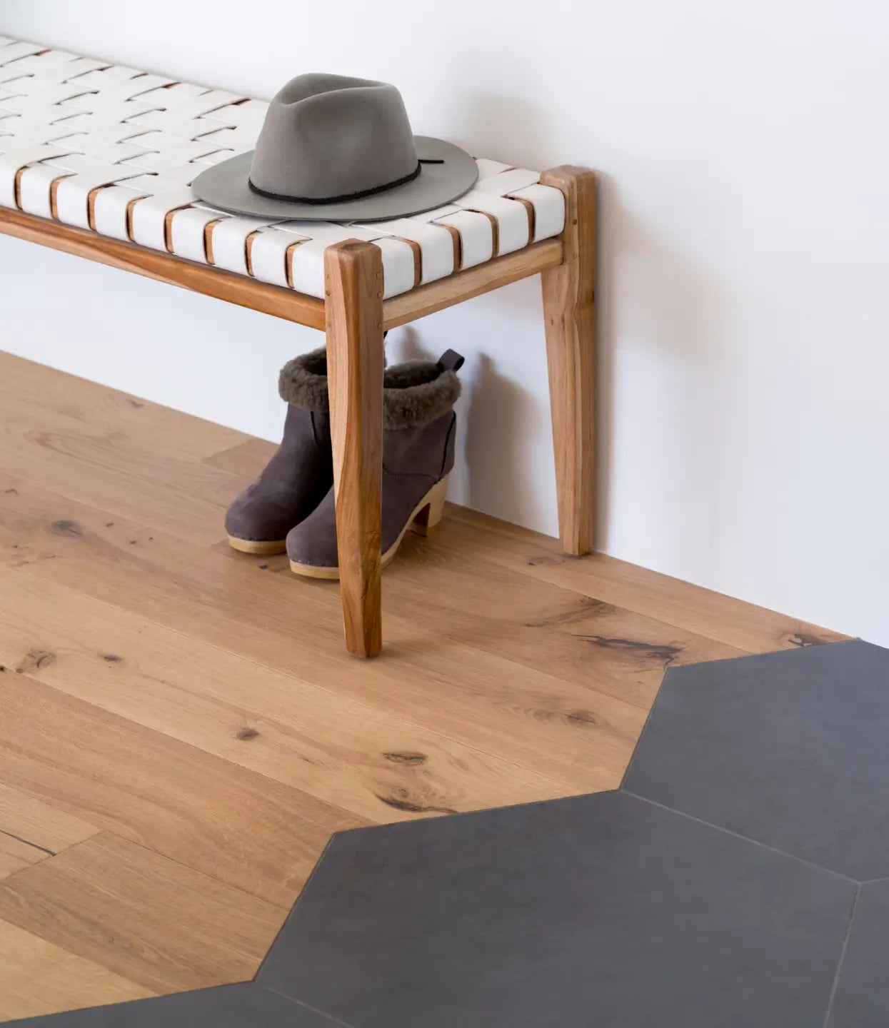 Transition from white oak flooring to black hexagon tile in a geometric pattern