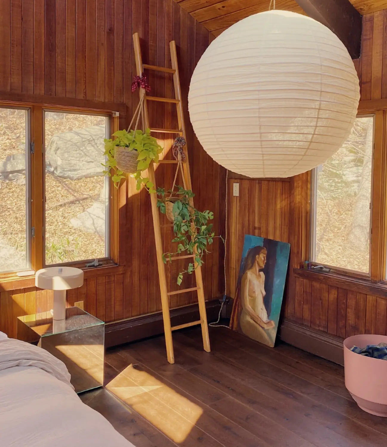 Retro wood paneled room with paper lantern and dark wood flooring by Stuga