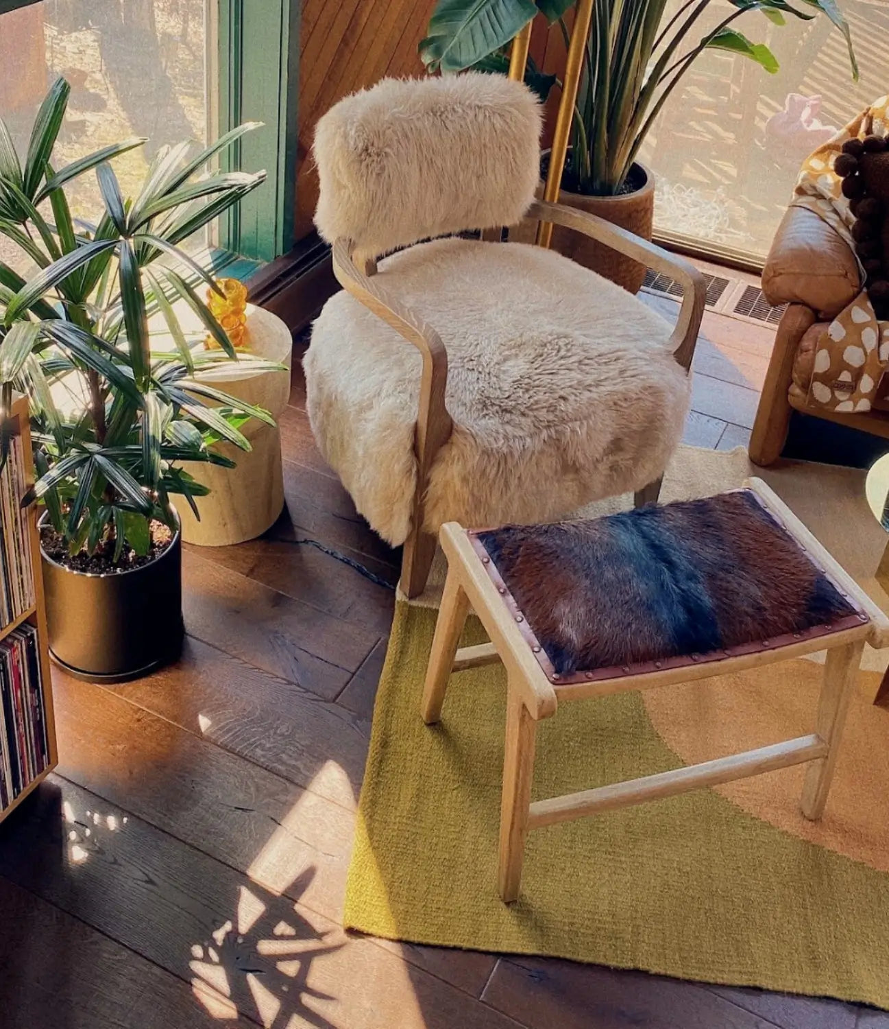 Living room corner with plants and modern furniture on dark wood flooring by Stuga