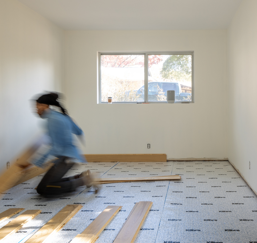 Man DIY installing white oak hardwood flooring in a bedroom