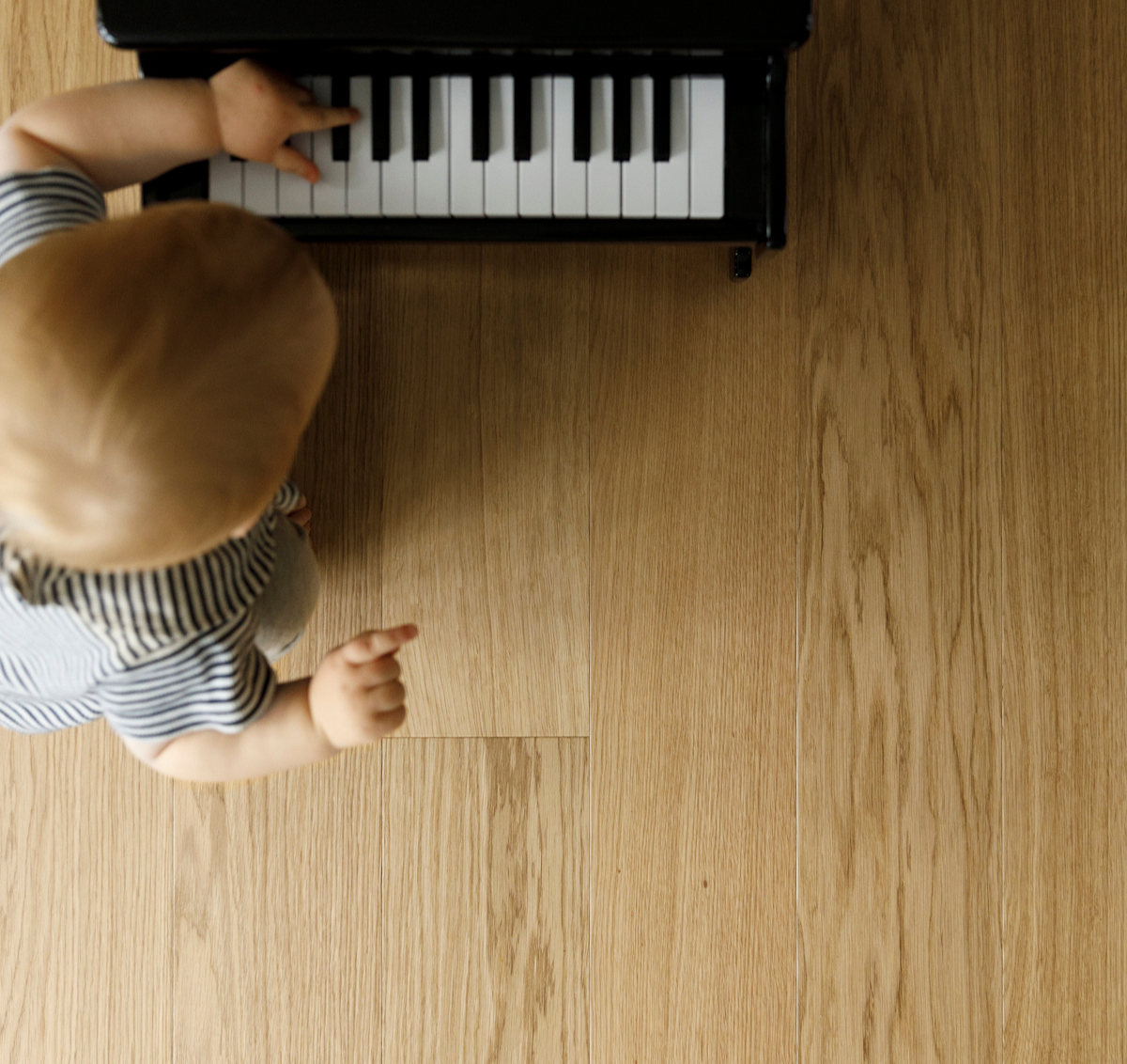 A baby playing toy piano on a waterproof hardwood floor