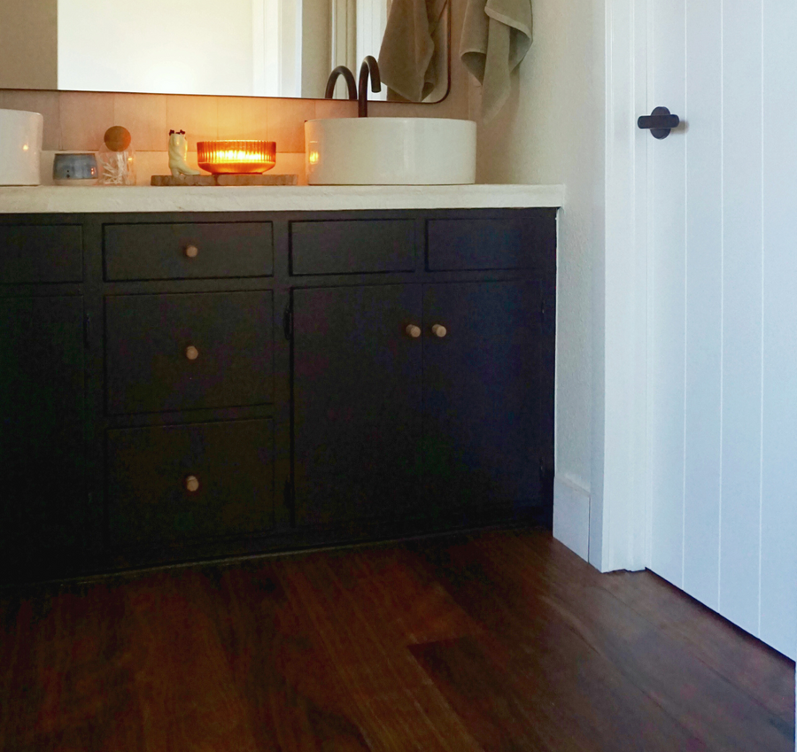 Walnut flooring in a modern bathroom with black cabinets and tadelakt counters