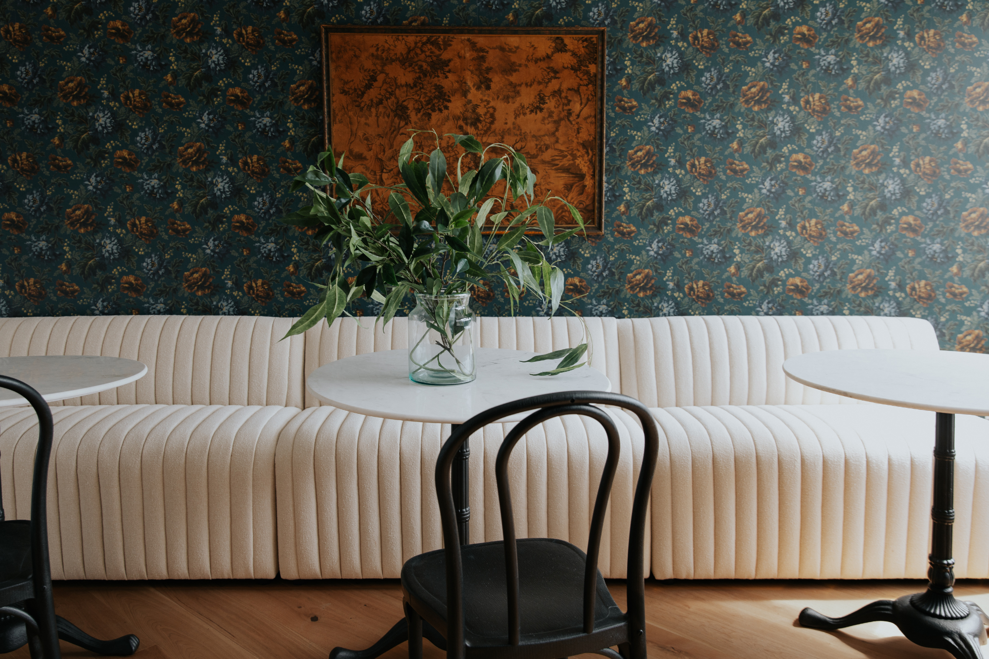 Floral wallpaper and banquette with hardwood flooring in Chris Loves Julia office