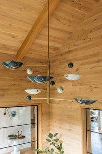 Modern chandelier hanging from ceiling clad with Stuga wood flooring and wood walls