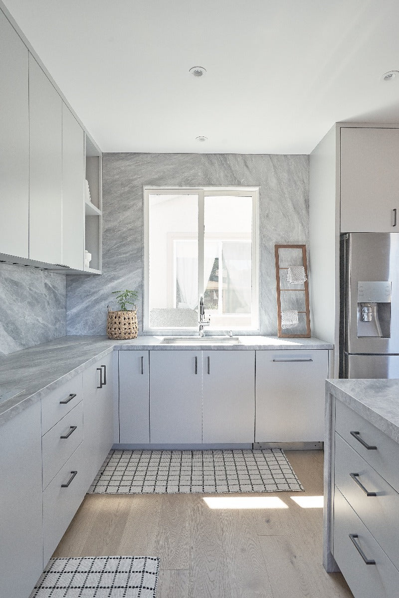 Modern matte hardwood flooring in a minimalistic kitchen with white cabinets and natural stone