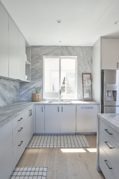 Modern matte hardwood flooring in a minimalistic kitchen with white cabinets and natural stone