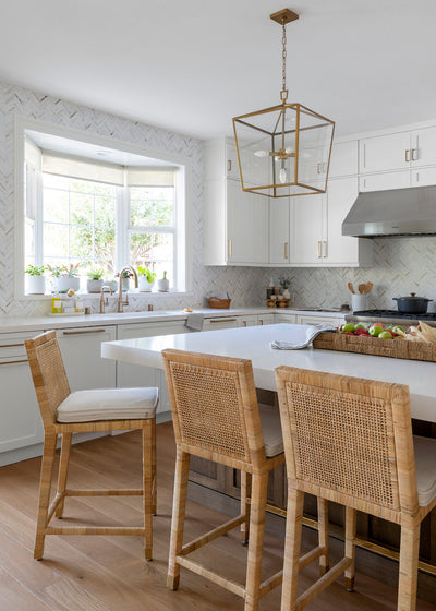 Faye wood flooring by Stuga x CLJ in a white kitchen with woven counter stools