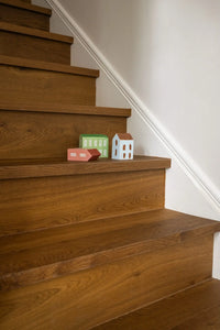 Wooden staircase with small model houses on a white wall background