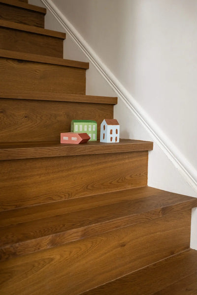 Wooden staircase with small model houses on a white wall background