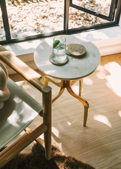 A table with a drink on top of a blonde hardwood floor