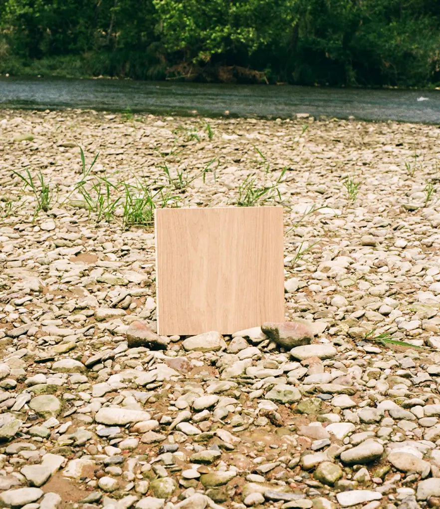 12 inch wide plank flooring sample on a bed of rocks by a river