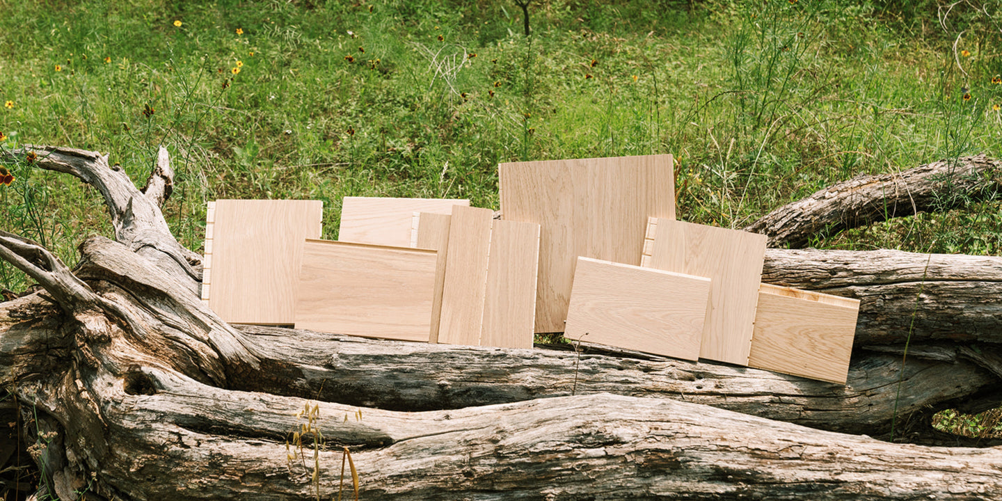 A group of blonde hardwood floor samples in varying plank widths on a fallen tree