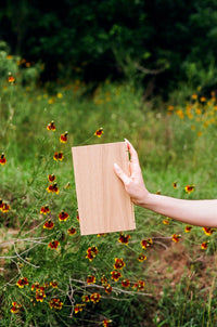 Astrid white oak flooring sample being held in a field of Texas wildflowers