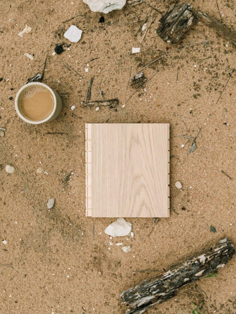 Fika wood flooring sample by Stuga with a cup of coffee on a sand bank
