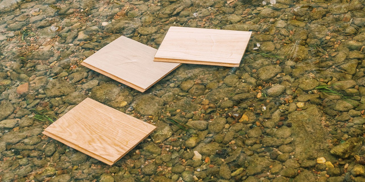 Three waterproof wood flooring samples in a natural river