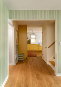 Hallway with wooden floor, striped walls, and a staircase.
