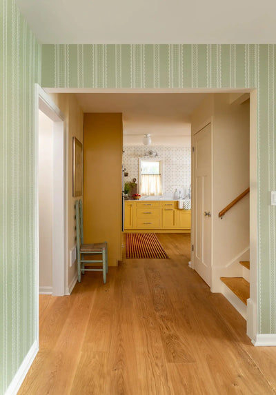 Hallway with wooden floor, striped walls, and a staircase.