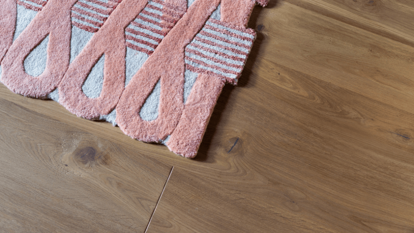 Wide plank engineered hardwood flooring from Sweden with a pink geometric rug