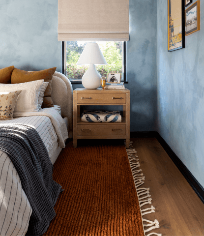 Harbor flooring by Stuga hand scraped white oak in a bedroom with blue limewash walls and a rust red rug