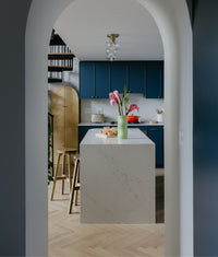 Modern blue kitchen with natural oak herringbone wood flooring