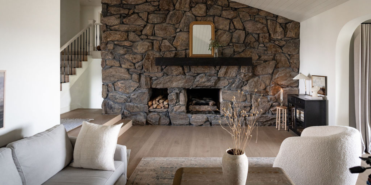 A living room with stone fireplace and matte hardwood flooring by Stuga