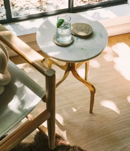 A table with a drink on top of a blonde hardwood floor