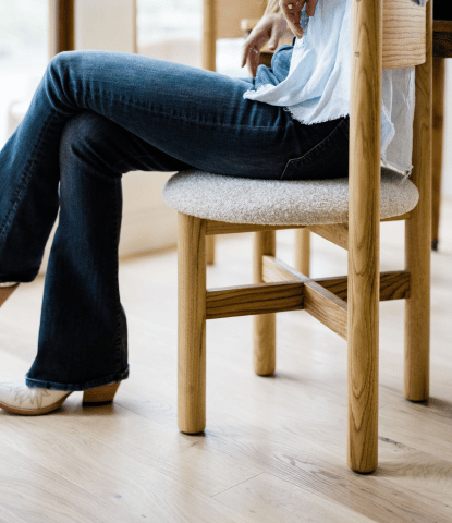 Closeup of a woman sitting on a modern dining chair on white oak flooring by Stuga