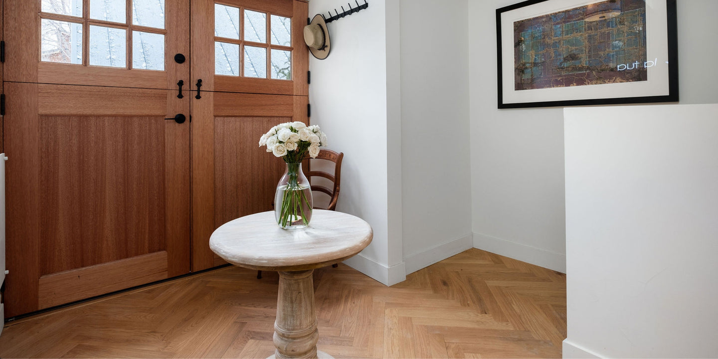 Herringbone wood flooring by Stuga laid in an entryway with wood doors