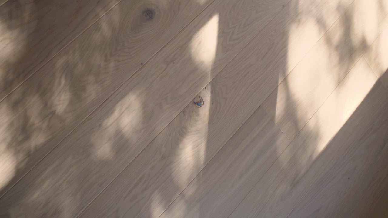 Dappled light shadows on planks of Fika Scandinavian flooring by Stuga