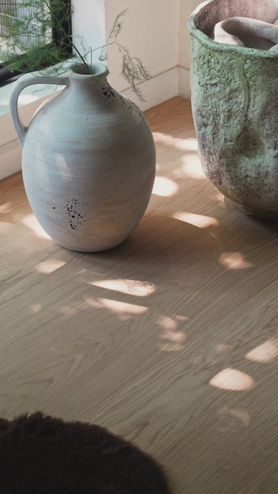 Dappled light shadows on a modern white oak floor with stone planters