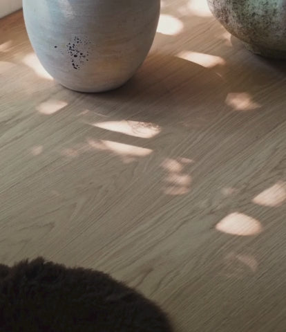 Dappled light shadows on a modern white oak floor with stone planters