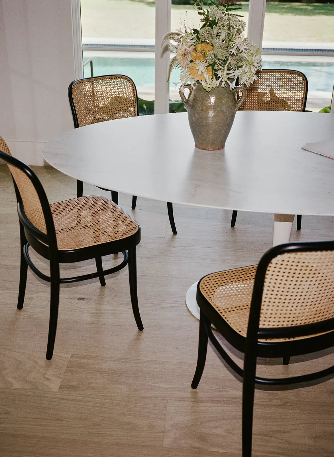 Blonde wood flooring under a tulip table 