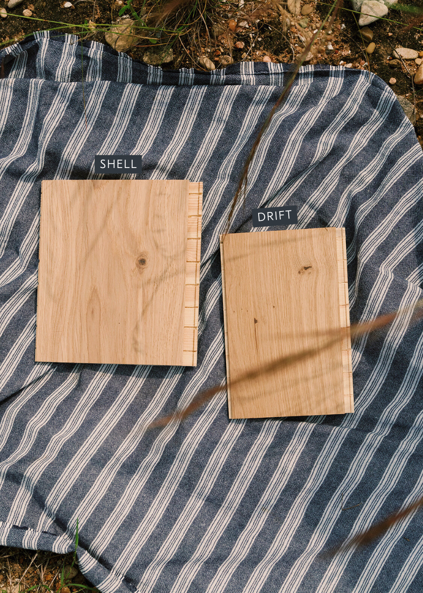 Two wood flooring samples on a striped blanket with labels reading "shell" and "drift"